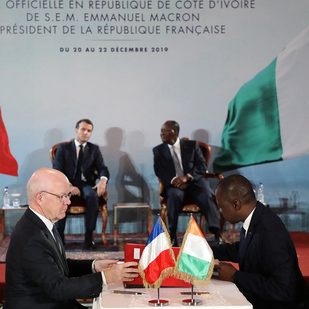 Philippe Bonnave, ex-CEO of Bouygues Construction (left), and Ivorian Minister of Transport Amadou Koné sign Abidjan metro project in the presence of French President Emmanuel Macron and Alassane Ouattara in Abidjan, in December 2019.