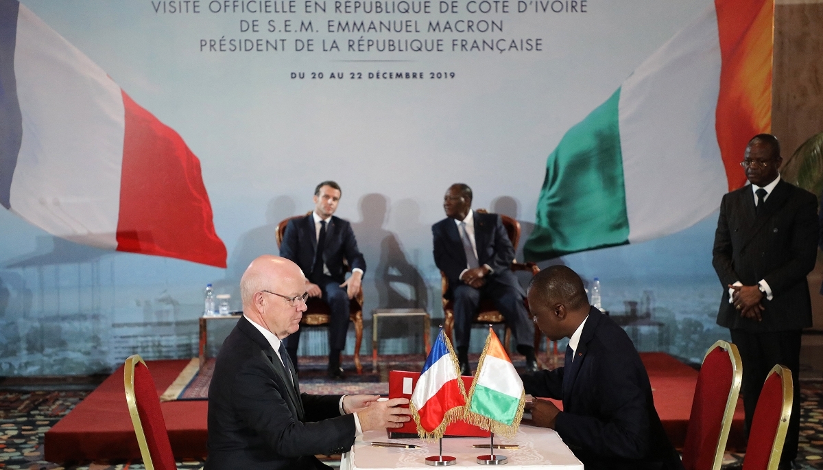 Philippe Bonnave, ex-CEO of Bouygues Construction (left), and Ivorian Minister of Transport Amadou Koné sign Abidjan metro project in the presence of French President Emmanuel Macron and Alassane Ouattara in Abidjan, in December 2019. 