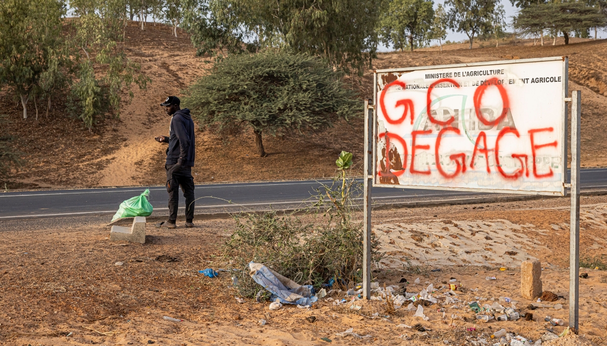 A man stands next to a sign that reads 'Grande Cote Operations (the former name of Eramet Grande Cote) Leave' in Lompoul, 11 February 2025.