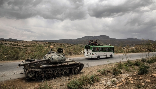 A bus carrying civilians passes a destroyed tank outside Mekele in Ethiopia's Tigray region, in June 2021. 