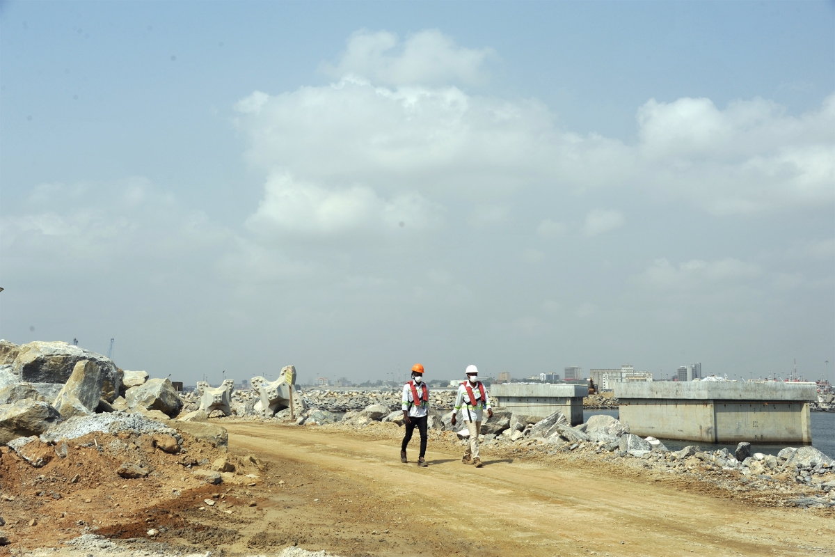 Ghanaian workers walk at the construction site of Tema Liquefied Natural Gas (LNG) Import Terminal Project in Tema, Ghana, on 5 January 2021.
