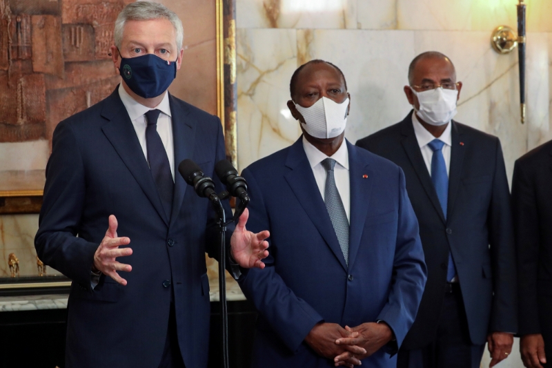 French Economy Minister Bruno Le Maire stands with Ivorian President Alassane Ouattara and Prime Minister Patrick Achi during his visit to Abidjan, Ivory Coast, on April 30, 2021.