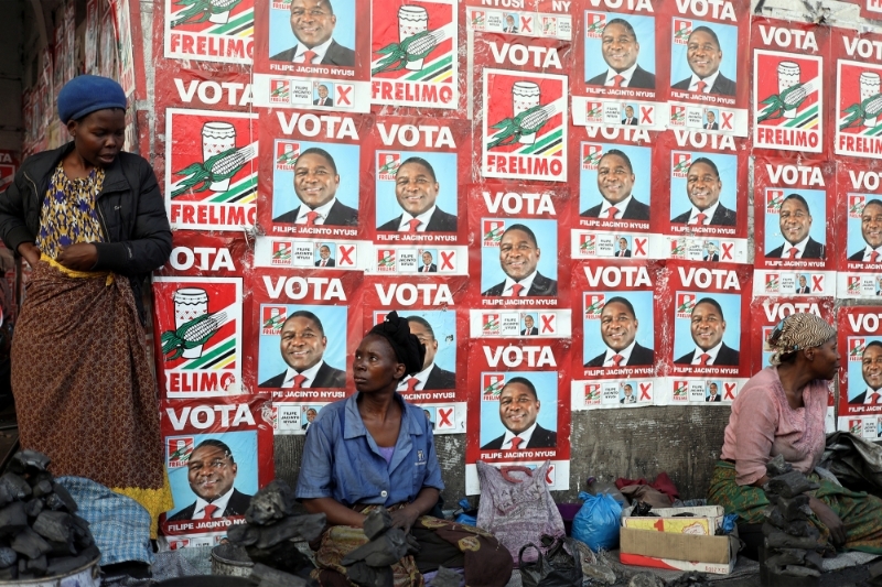 Women, selling charcoal, chat in front of the ruling FRELIMO party election posters in the capital, Maputo, Mozambique August 31, 2019.