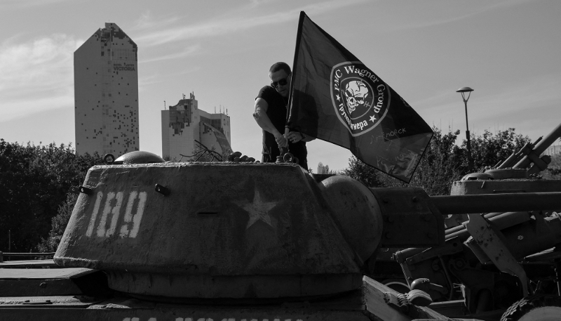 A man attaches a Wagner flag to a tank in Donetsk, Russian-controlled Ukraine, on 1 October 2023.
