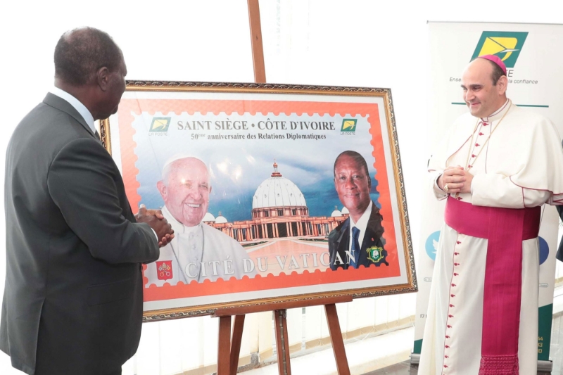 Alassane Ouattara and Apostolic Nuncio Paolo Borgia during the unveiling ceremony of the commemorative stamp of the 50th anniversary of the establishment of diplomatic relations between Ivory Coast and the Vatican.